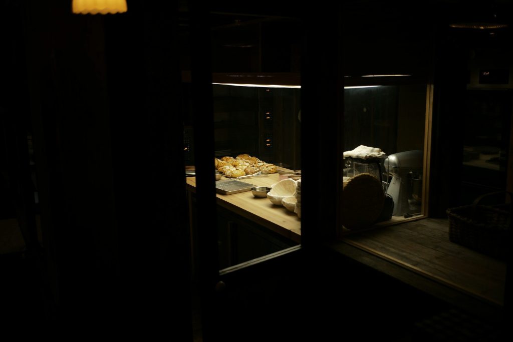 A locked oven door in a near-black kitchen, the fascia dark and the handle catching one cold light